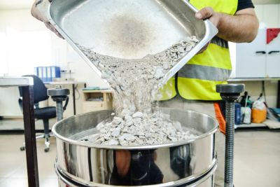 Person pouring crushed concrete into a sieve.