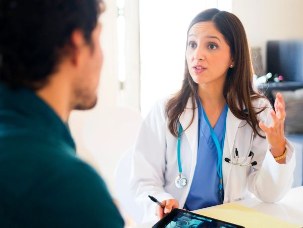 Female doctor explaining medical results to a male patient using a tablet.