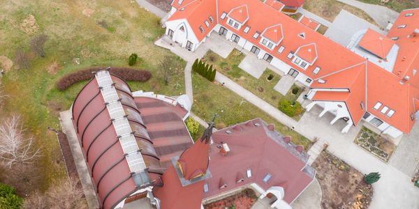 Aerial view of buildings with red roofs and pathways in a landscaped area.