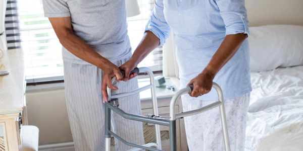 Caregiver assisting elderly person with walker.