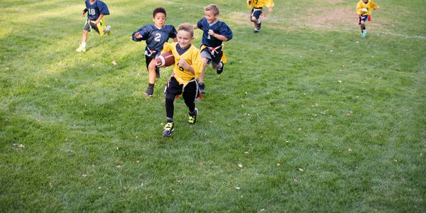 Young boys playing flag football on a grassy field.