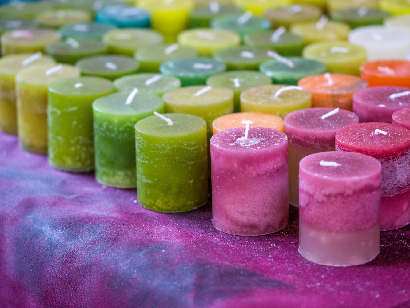 Colorful cylindrical candles arranged on a purple surface.
