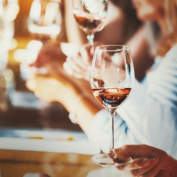 People looking at glasses of wine with paper and a pen on the table as they learn about the wine