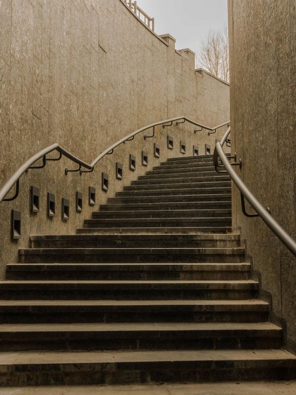 Curved stone staircase with metal railings and recessed lights along the wall.