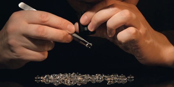 A jeweler inspects a diamond with a loupe and tweezers.