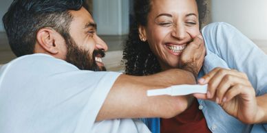 Happy couple joyfully celebrating pregnancy news with a positive test.