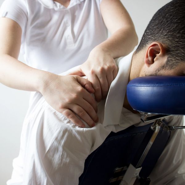 A person receiving a shoulder massage while seated on a massage chair.