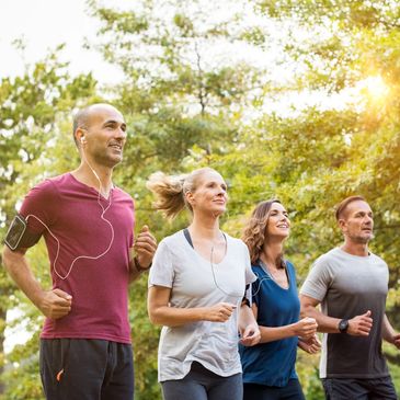 group of 2 men and 2 women running and exercising outside , they are in their late 30 s or early 40s