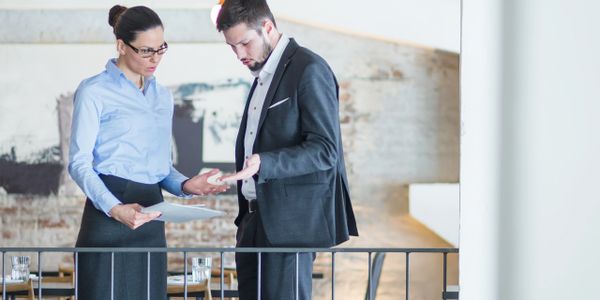 Two business professionals discussing documents in an office setting.