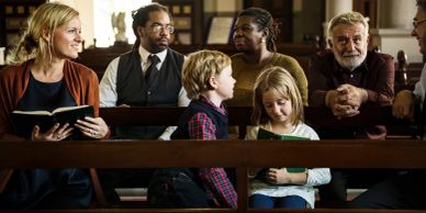 People seated on a bench inside a church or formal setting.