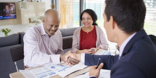 Businessmen shaking hands while a woman smiles during a meeting.