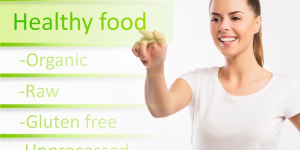 Smiling woman pointing at a digital board listing healthy food qualities.