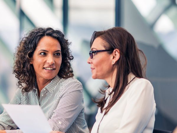 Two professional women discussing a document in a modern office.