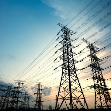 Power transmission towers silhouetted against a colorful sky.