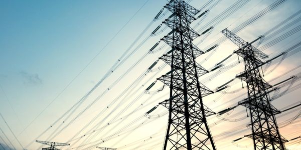 High-voltage power lines and towers against a sunset sky.