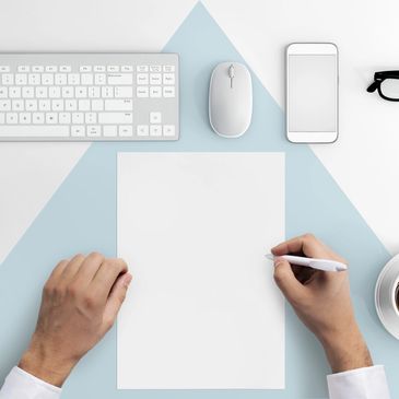 Minimalist workspace with keyboard, mouse, phone, glasses, coffee, and blank paper.
