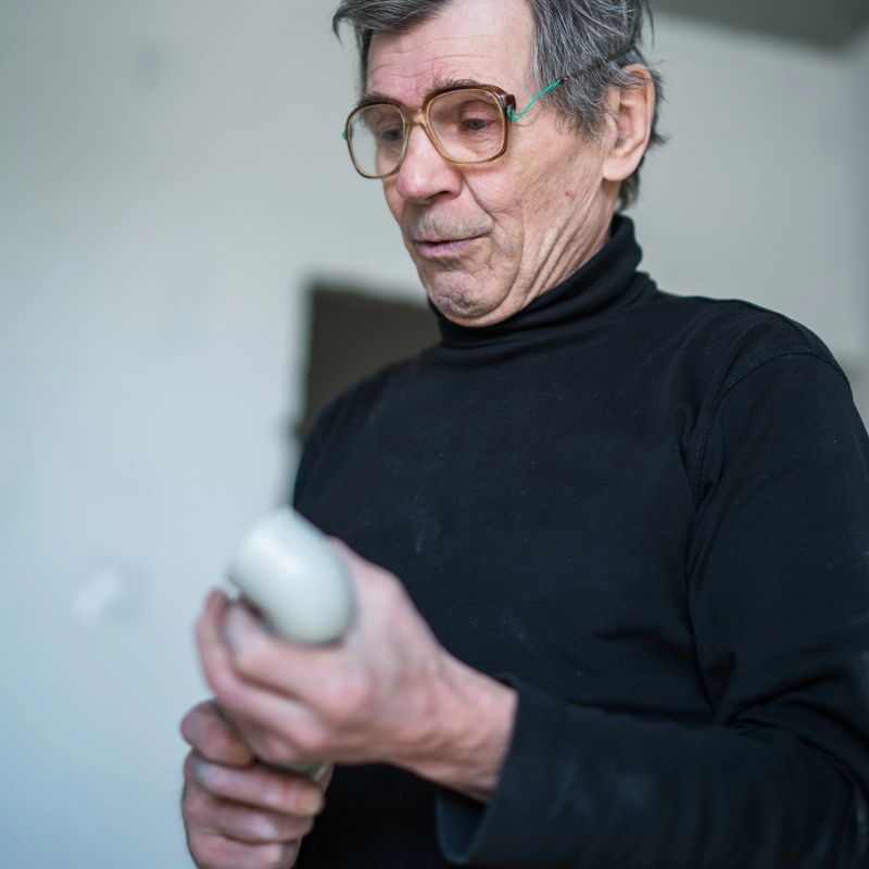 70-years-old active senior man, construction worker - plumber, working indoor for home renovation in the new residential apartment in Minsk, Belarus, Eastern Europe. New apartments in Belarus are purchasing in most cases without any finishing, and buyers doing the final stage of construction by his own expenses, sometimes by themself.