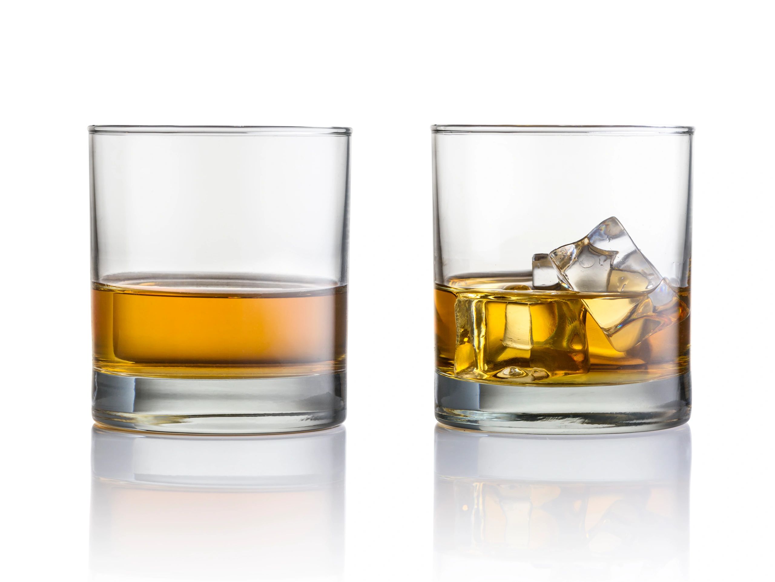 Two glasses of whiskey, one with ice cubes.