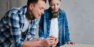 Man teaching a young girl about gun safety at a shooting range.