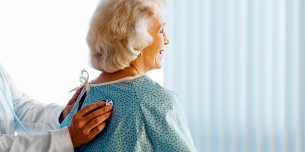 Doctor examining elderly woman with a stethoscope during a check-up.