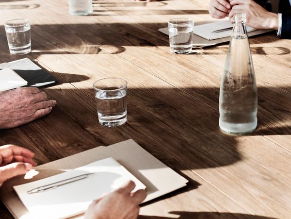 Business meeting setup with water glasses and documents on a wooden table.