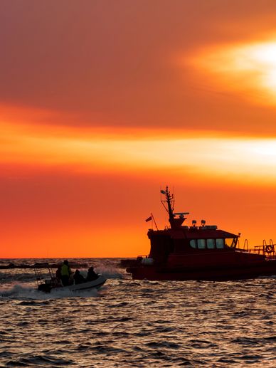 Two boats on water during a vibrant orange sunset.
