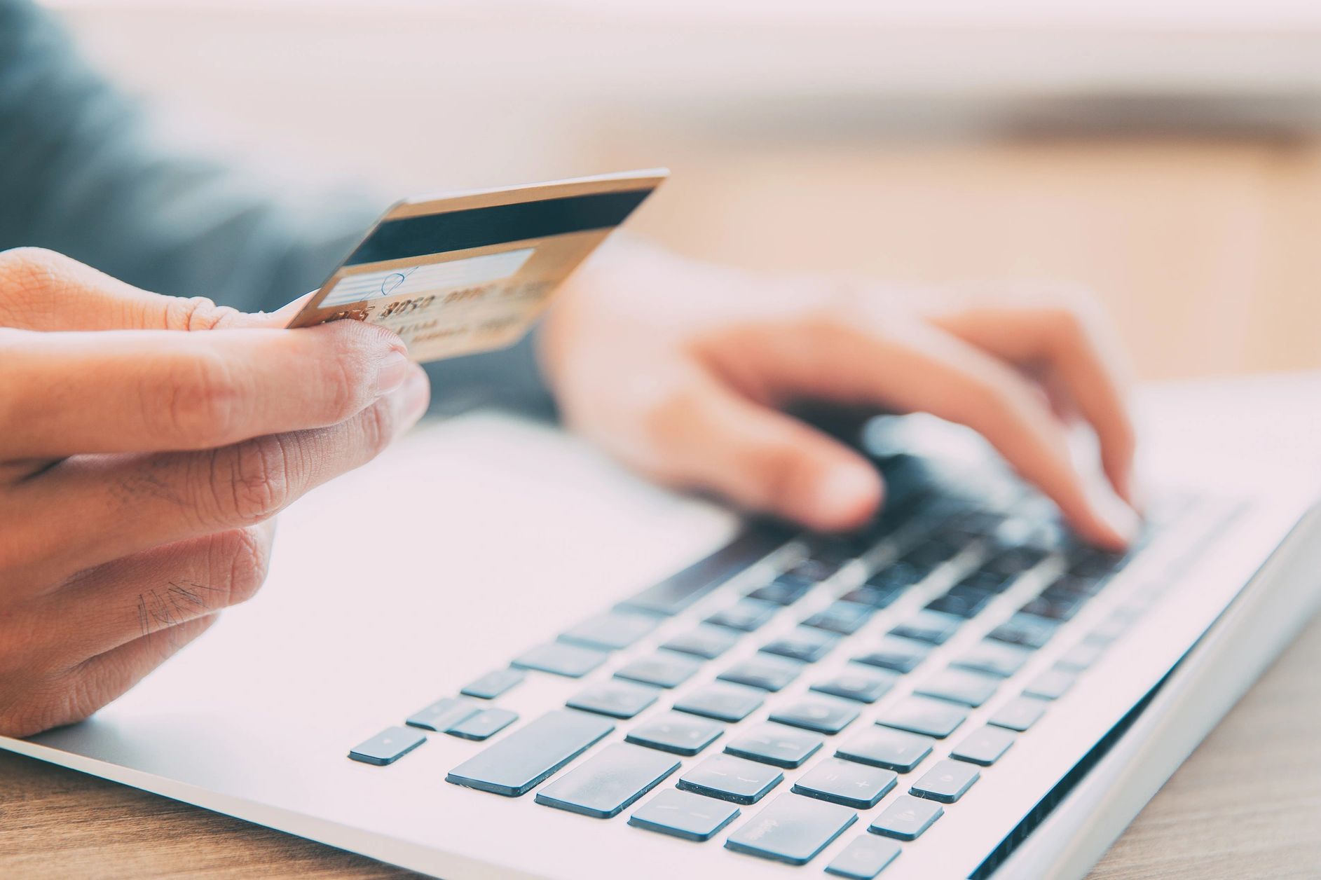 Person holding credit card and using laptop.
