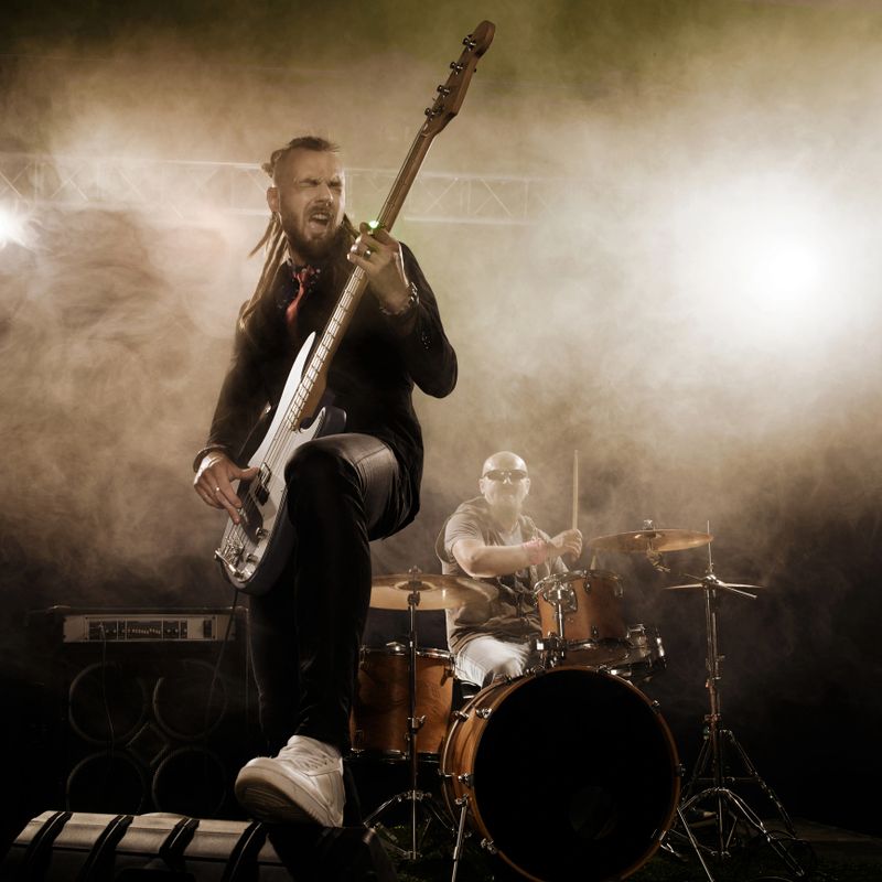 Rock band performs on stage. Bassist in the foreground. Close-up.