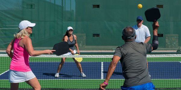 Four people playing pickleball on an outdoor court.