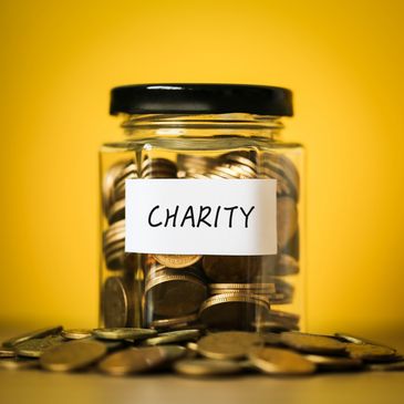 A jar labeled 'Charity' filled with coins against a yellow background.