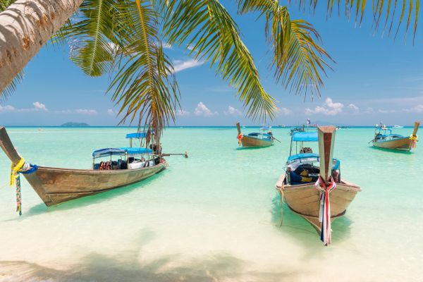 Traditional wooden boats on clear tropical water with palm trees.