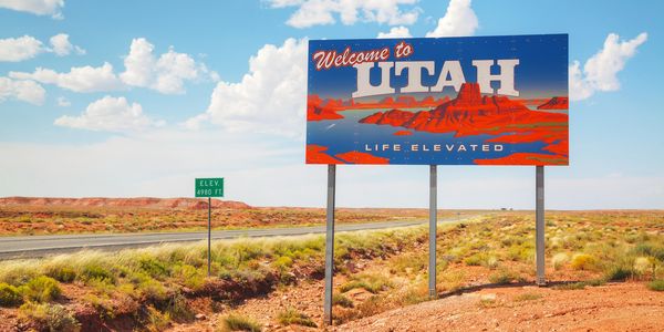 Welcome sign for Utah with desert landscape and elevation marker.