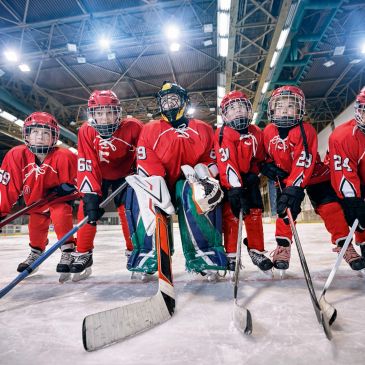 Youth ice hockey team in red uniforms posing on ice rink.