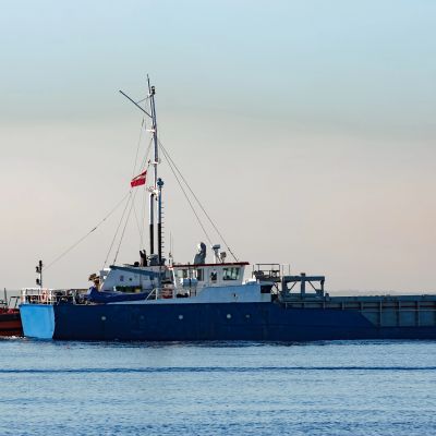 A blue and white cargo ship on calm water.