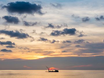 Boat on calm water during sunset.