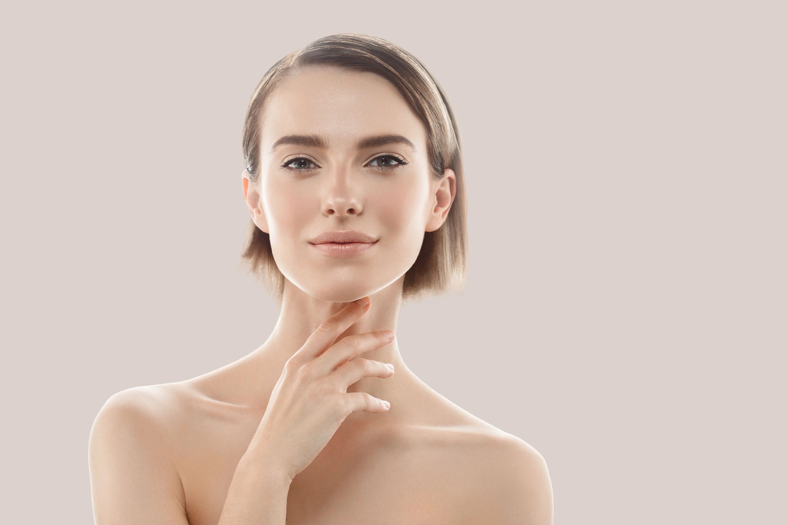 Woman with calm, natural expression and smooth skin on a warm neutral background