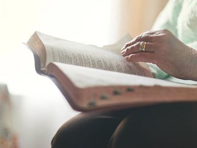 A person reading a book with focus on the hand turning pages.