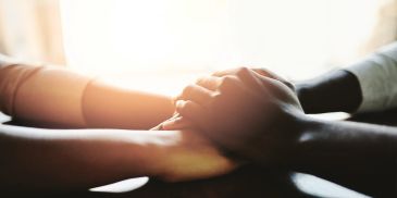 Two people holding hands in a comforting gesture.