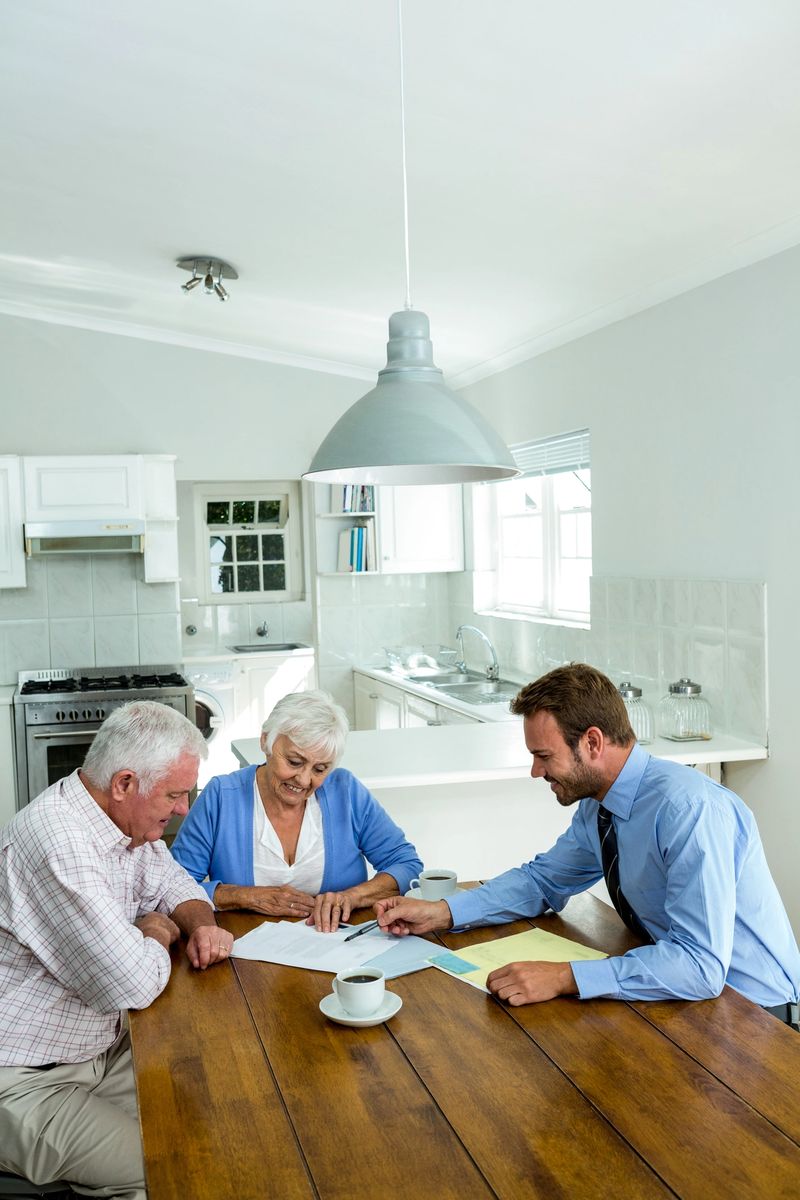 Senior couple with agent while sitting at table in home