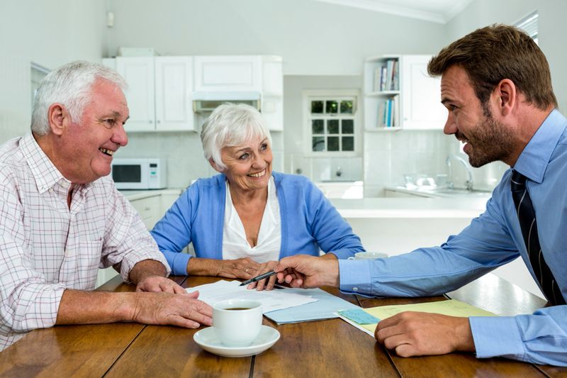 Happy couple with agent while sitting at table in home