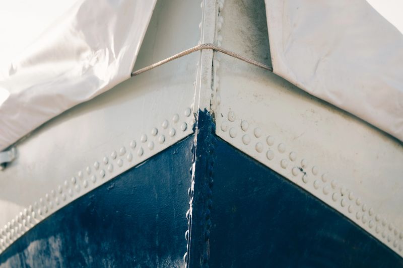 Cropped image of a metal boat covered with tarpaulin, close-up