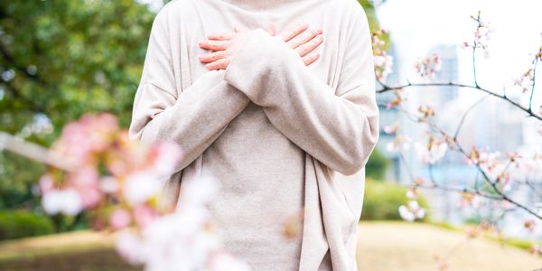 Woman with arms crossed over chest, wearing a comfortable sweater surrounded by calming nature