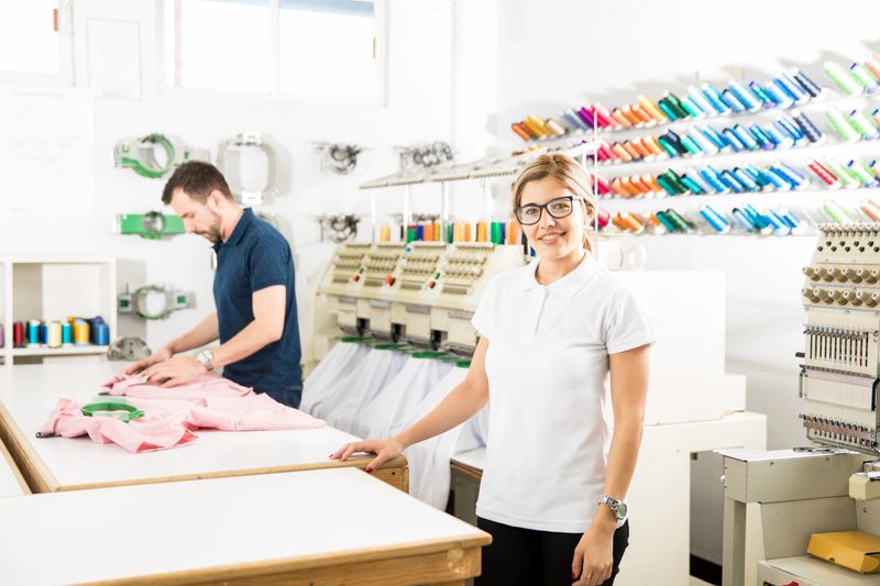 Confident and beautiful female business owner standing in front of her textile factory