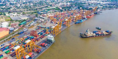 Aerial view of a busy shipping port with containers and cranes.