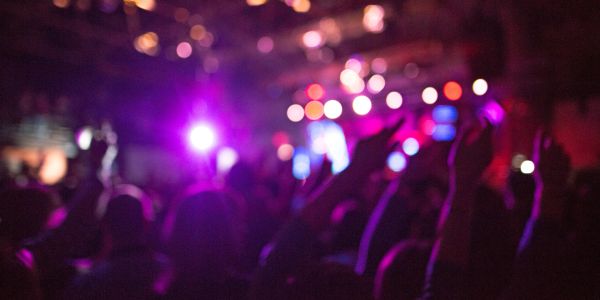 Blurred crowd at a vibrant concert with colorful lights.