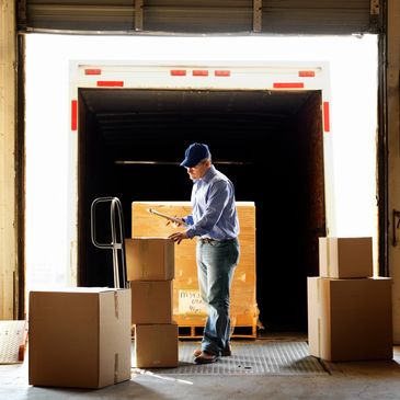 Worker scanning boxes at a warehouse loading dock.