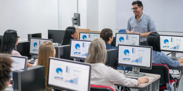 Instructor teaching students data analysis on computers.