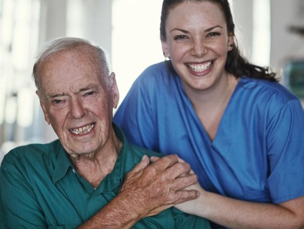 Elderly man with nurse sharing a warm moment in a bright room.