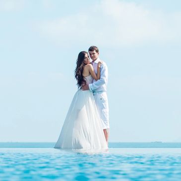 Bride and groom stand by water at luxury wedding at Zoetry Paraiso De La Bonita under clear skies.