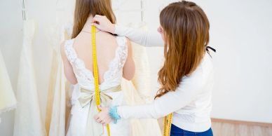 Woman measuring dress on another woman.